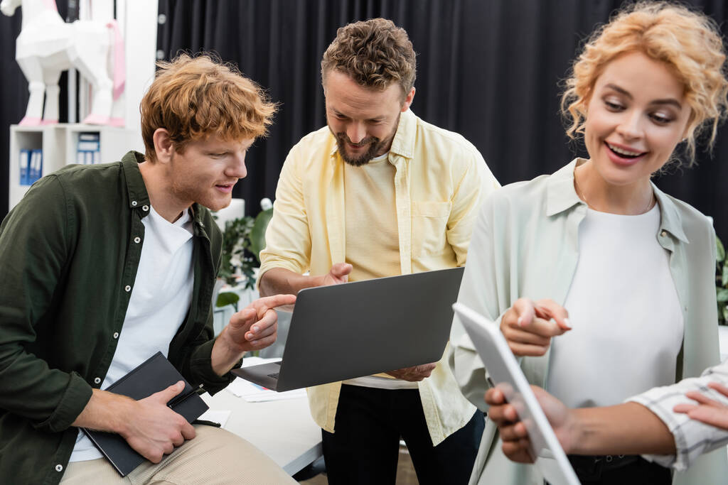 pozitív üzleti emberek rámutatva laptop és digitális tablet, miközben dolgozik az irodában - Fotó, kép