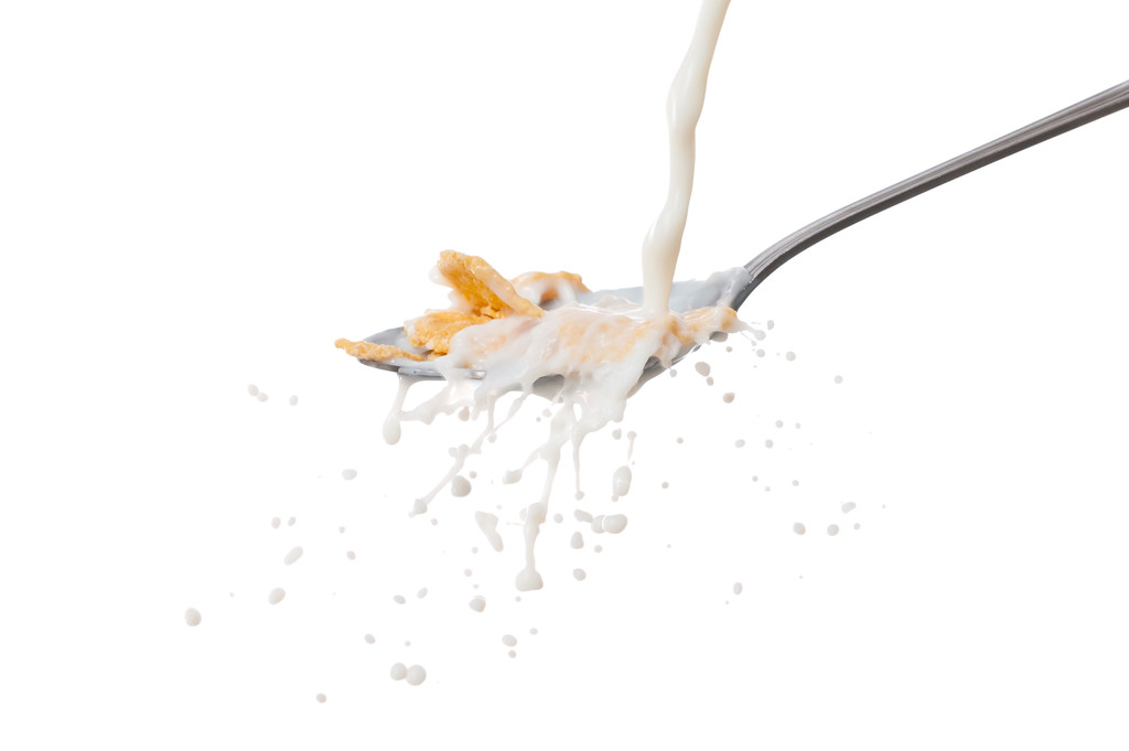 Salpicadura de leche en la cuchara con copos de maíz
 - Foto, Imagen