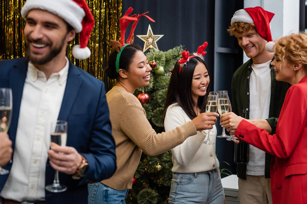 Negócios multiculturais pessoas clinking champanhe perto da árvore de Natal no escritório  - Foto, Imagem