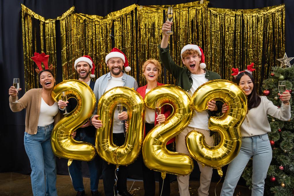 Веселі міжрасові ділові люди тримають шампанське і повітряні кулі у формі 2023 року в офісі
  - Фото, зображення