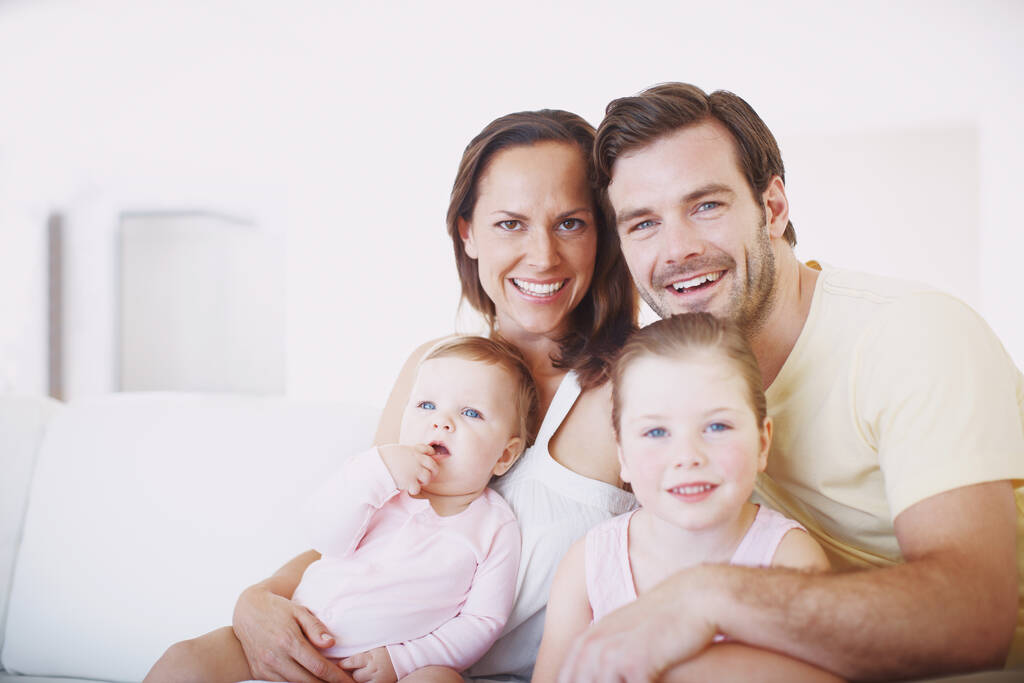 Zachytit blažený rodinný okamžik. Vystřižený portrét šťastné čtyřčlenné rodiny sedící těsně vedle sebe na pohovce uvnitř - Fotografie, Obrázek
