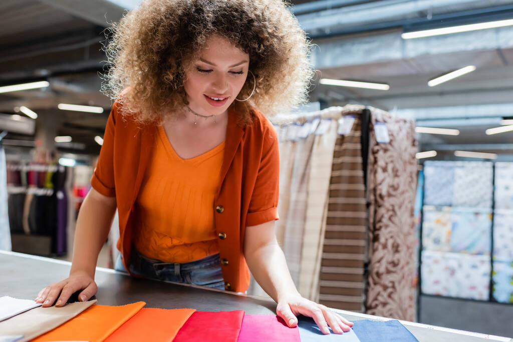Client joyeux regardant des échantillons de textiles colorés sur la table dans la boutique  - Photo, image