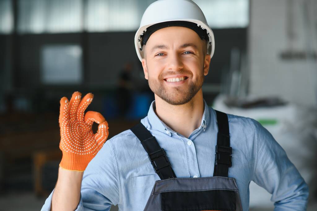 Porträt eines Fabrikarbeiters in Schutzuniform und Hard Hat, der an einer Industriemaschine am Fließband steht. Beschäftigte in der Industrie. - Foto, Bild