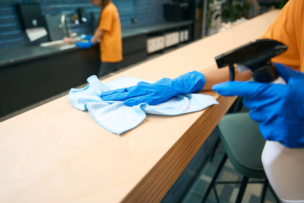 Schoonmaakbedrijf werknemers in uniform schoon en desinfecteren oppervlakken, ze gebruiken speciale gadgets - Foto, afbeelding