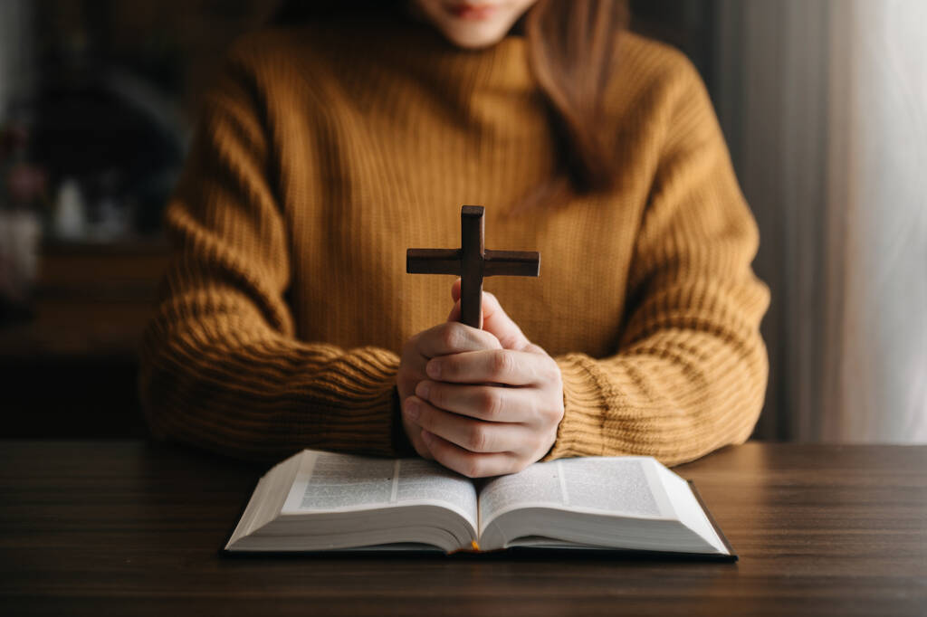 cropped view of religious woman praying, Hands at table with cross and bible book  - Photo, Image