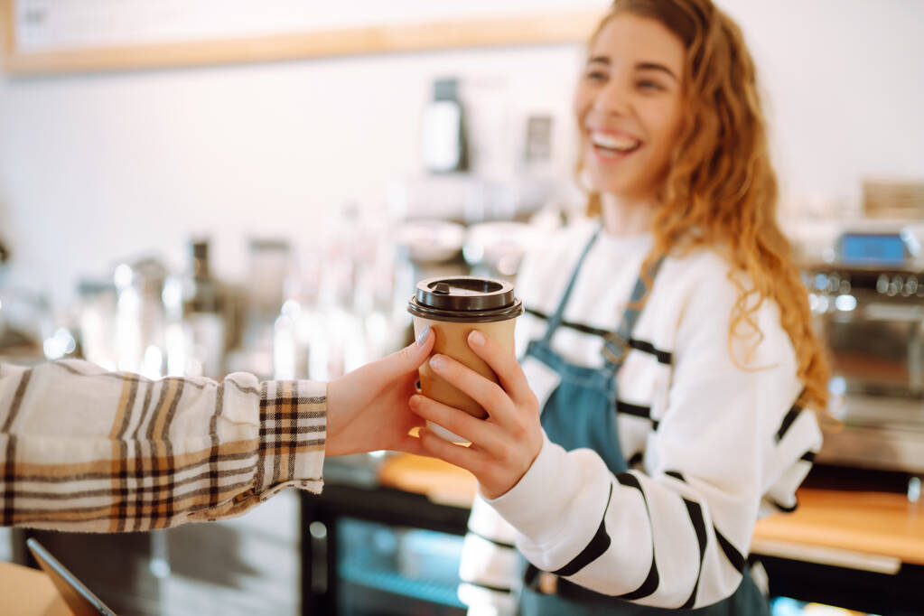 Souriant barista- fille donnant emporter tasses à café à un client.   - Photo, image