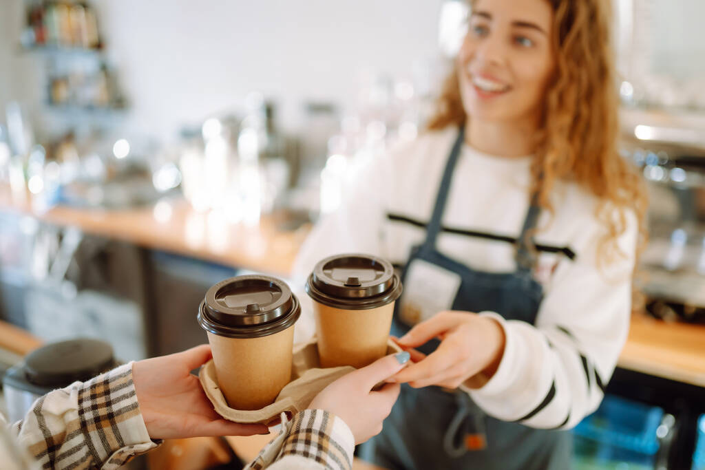 Sorrindo barista- menina dando tirar xícaras de café para um clientes.   - Foto, Imagem