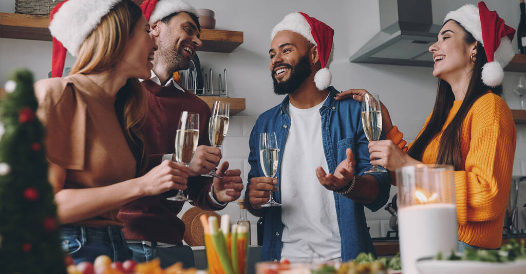 Krásní mladí lidé mluví a usmívají se, zatímco si užívají vánoční večeři doma - Fotografie, Obrázek