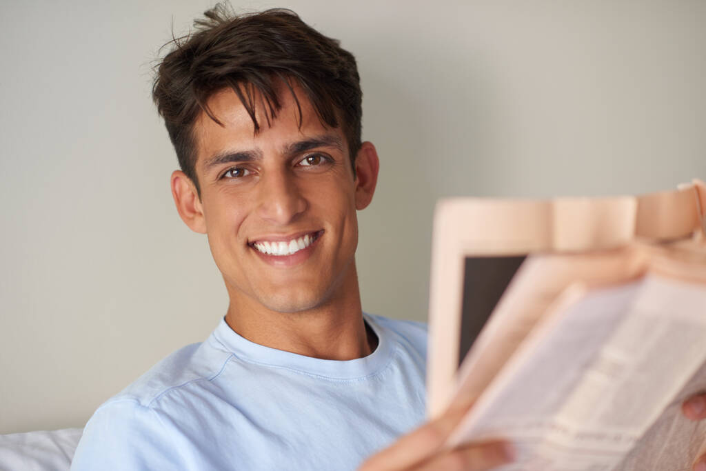 Zależy mi na rutynie. przystojny młody mężczyzna czytający gazetę w jego sypialni - Zdjęcie, obraz