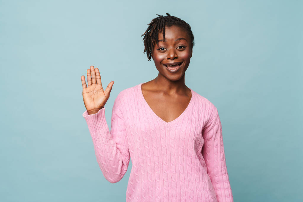 African american happy woman smiling and doing welcoming gesture with her hand isolated over blue background - Photo, Image