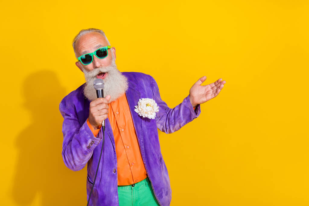 Foto de talentoso hombre funky vestido de moda colorido traje cantar karaoke club concierto espacio vacío aislado sobre fondo de color amarillo. - Foto, imagen