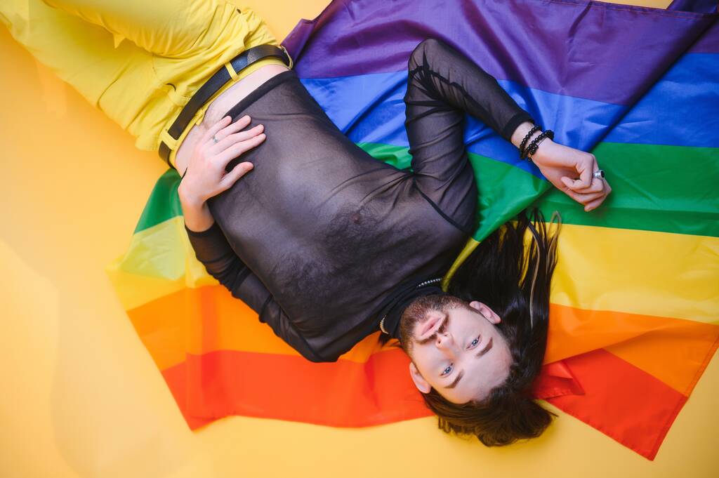LGBTQコミュニティの虹の旗のシンボルを持って楽しいゲイの男. - 写真・画像