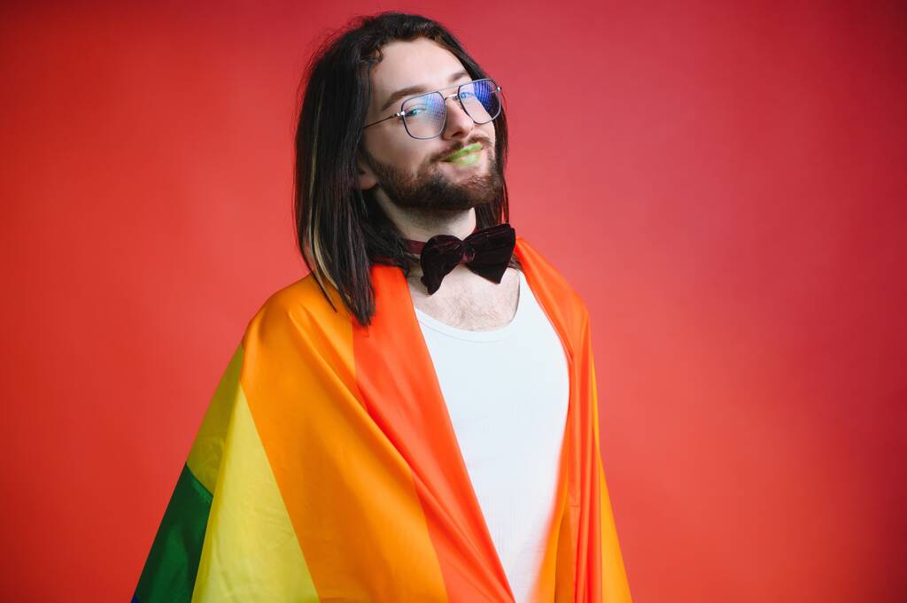 Gay man hold rainbow striped flag isolated on colored background studio portrait. People lifestyle fashion lgbtq concept. - Photo, Image