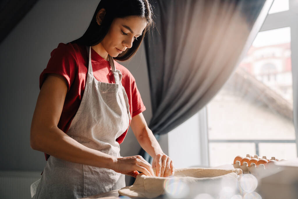 Jonge Spaanse vrouw draagt een schort om taart te bakken in de keuken thuis - Foto, afbeelding