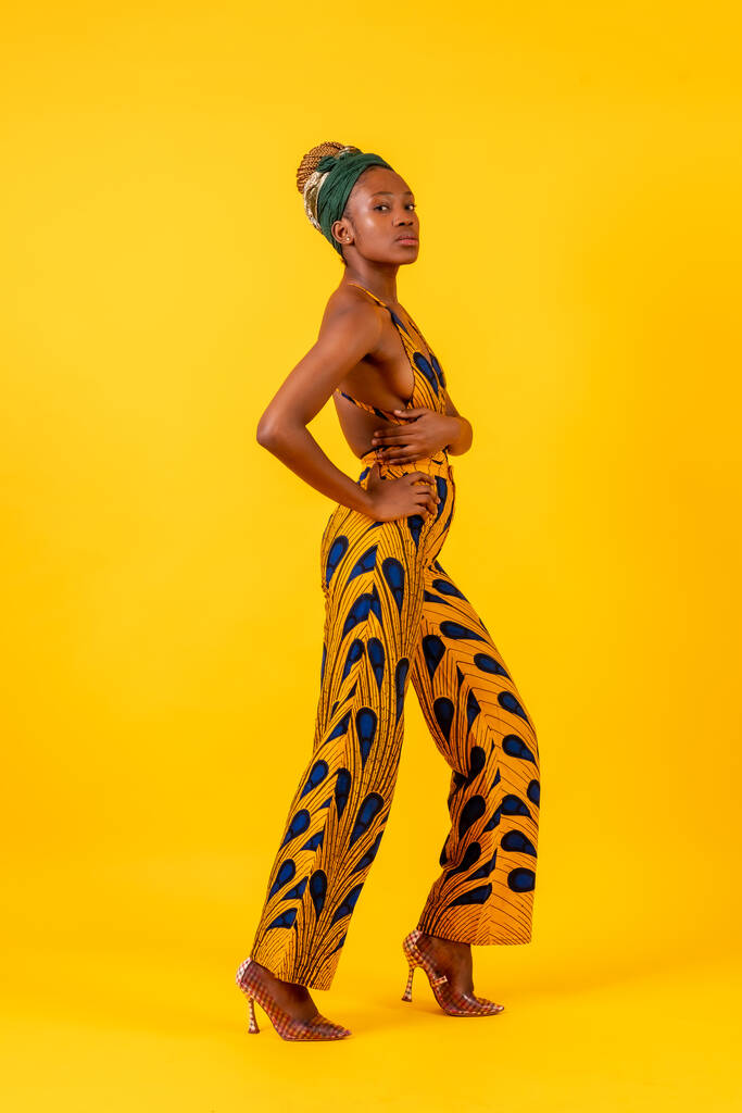Giovane donna africana in studio su sfondo giallo, costume tradizionale - Foto, immagini