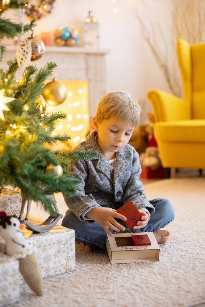 Aranyos óvodás gyermek, szőke fiú kisállat kutya, játszik díszített karácsonyi szobában otthon - Fotó, kép