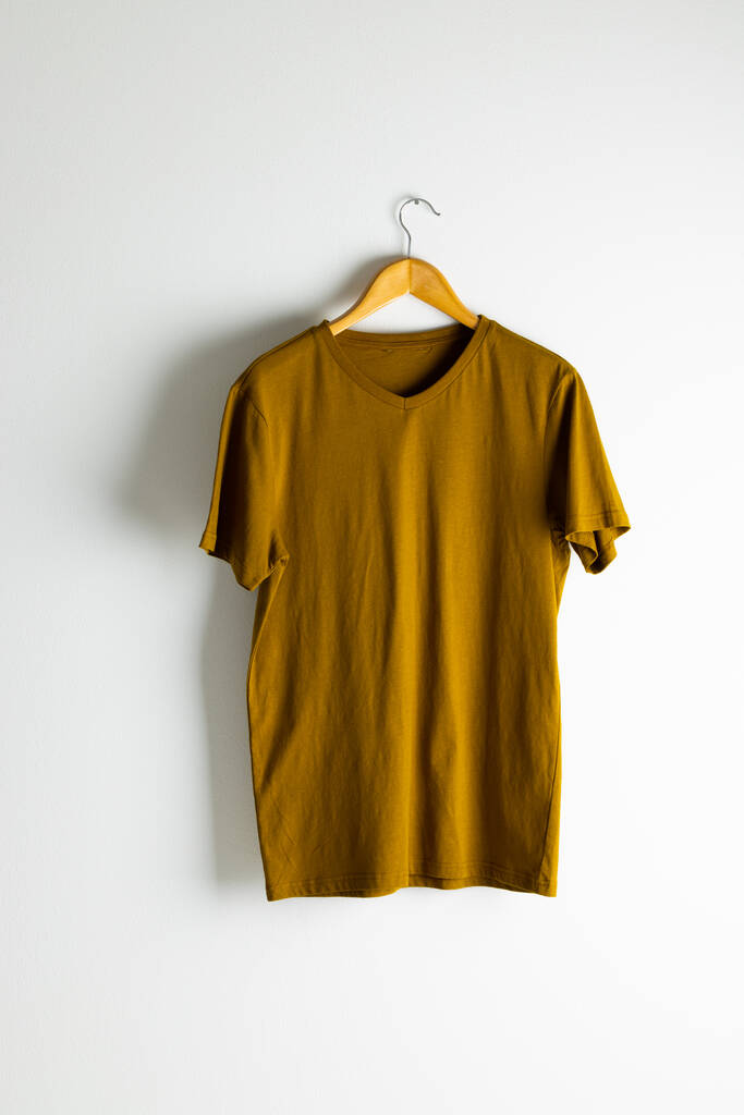 Tshirt appesa al appendiabiti e copiare spazio su sfondo bianco. Abbigliamento, moda e retail concept. - Foto, immagini