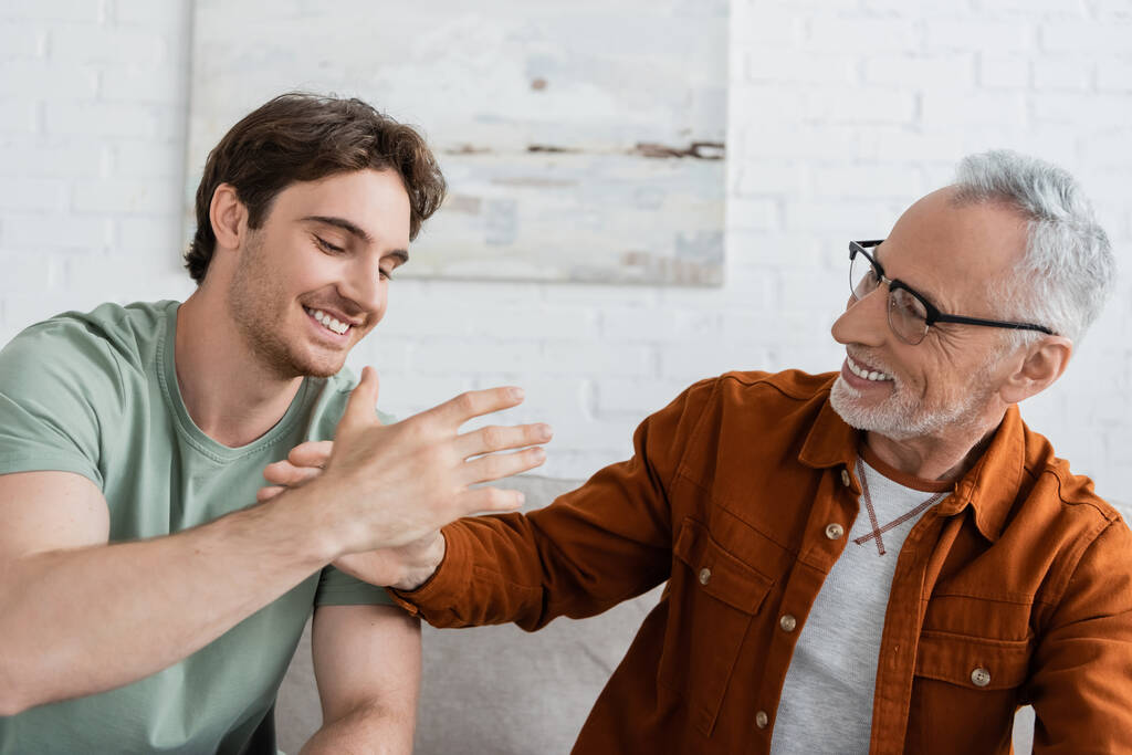 homme barbu gai dans les lunettes donnant haute cinq fils heureux à la maison - Photo, image