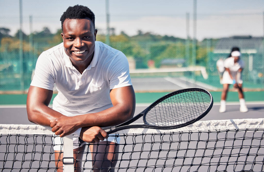 テニスコートでのトレーニング、モチベーションやスポーツのトレーニングのための笑顔でテニス、フィットネスの肖像画や黒人男性。健康、運動や健康のためのアスリート、幸福やテニス選手屋外ネット上で傾いて. - 写真・画像