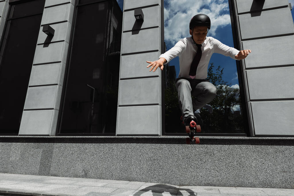 ヘルメットとローラースケートのビジネスマンは、都市部の通りにジャンプ  - 写真・画像