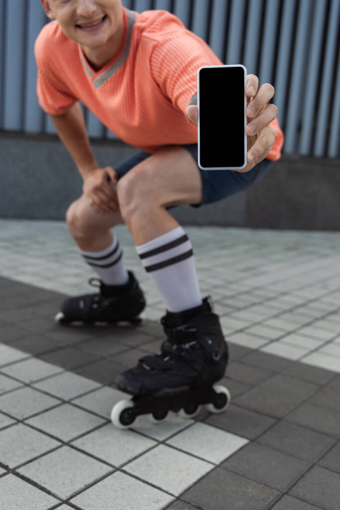 Περικοπή άποψη του θολή πατινέρ δείχνει smartphone με κενή οθόνη στο δρόμο  - Φωτογραφία, εικόνα