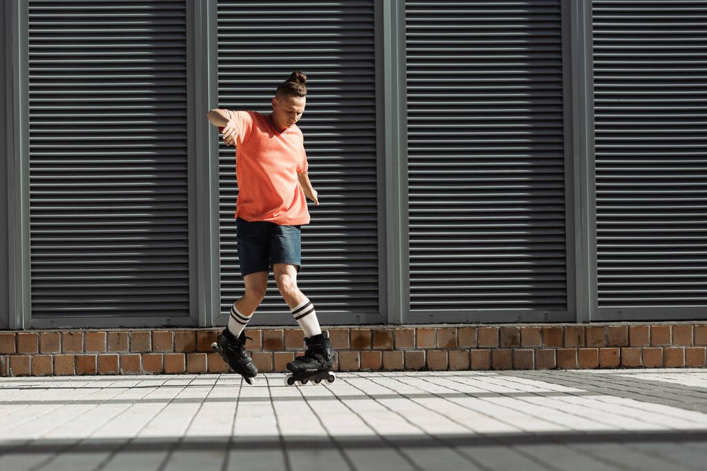 Fiatal görkorcsolyázó rövidnadrágban és térdzokniban trükközik a városi utcán  - Fotó, kép