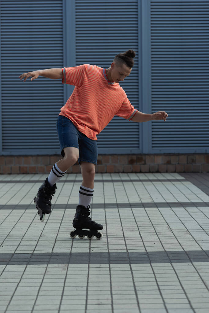 Молодой человек в роликовых коньках и шортах катается на природе  - Фото, изображение