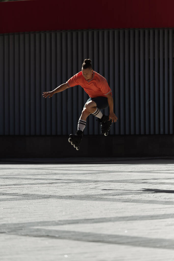 Jeune patineur à roulettes faisant un tour sur la place de la ville le jour  - Photo, image