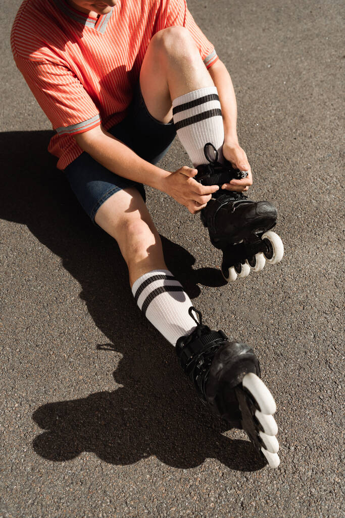 Ausgeschnittene Ansicht eines Mannes in kurzen Hosen mit Rollerblades auf Asphalt  - Foto, Bild