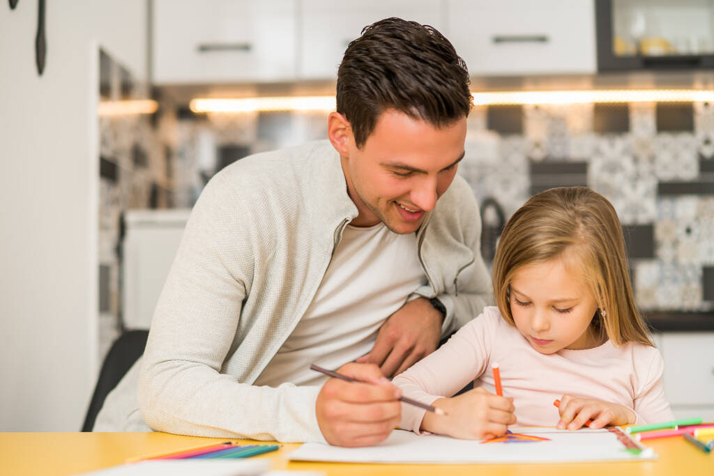 Το κοριτσάκι και ο πατέρας της απολαμβάνουν να ζωγραφίζουν μαζί στο σπίτι τους.. - Φωτογραφία, εικόνα