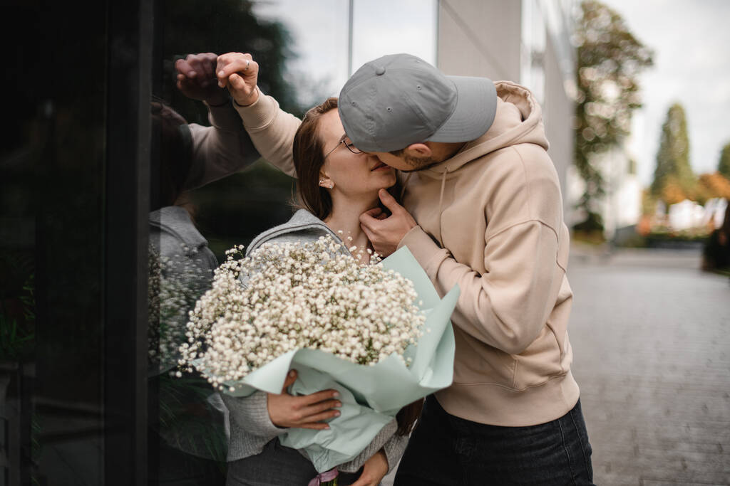 view of kissing couple in love, woman with lush flower bouquet and man. Romantic date. Love story - Photo, Image