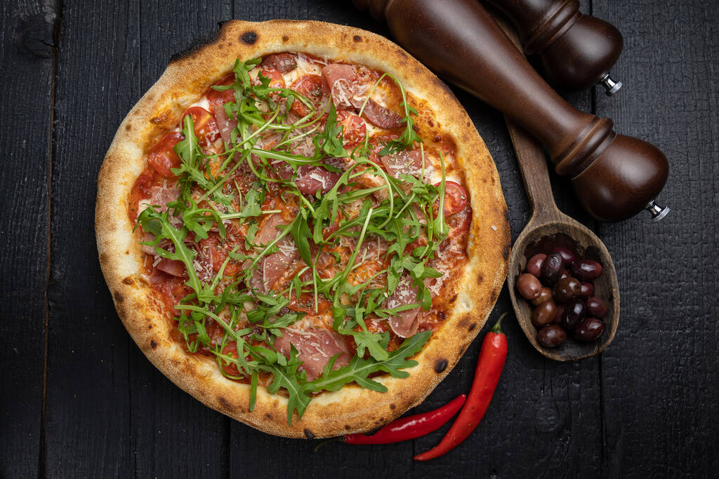 pizza savoureuse avec fromage et légumes sur une table noire en bois - Photo, image