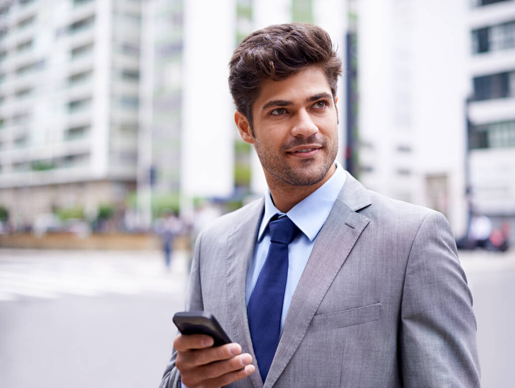 Moverse con su GPS móvil. Una foto recortada de un joven hombre de negocios guapo enviando mensajes de texto mientras camina por la ciudad - Foto, imagen