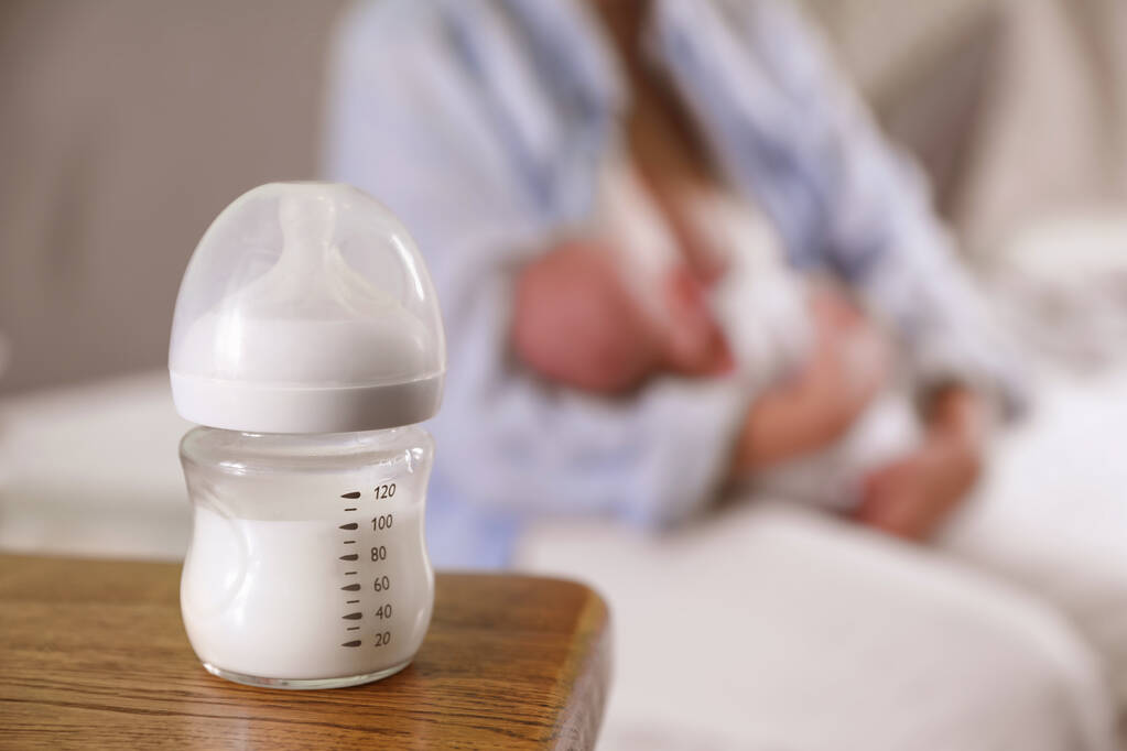Anne ve küçük bebeği evde, bir şişe süte odaklanıyor. Metin için boşluk - Fotoğraf, Görsel
