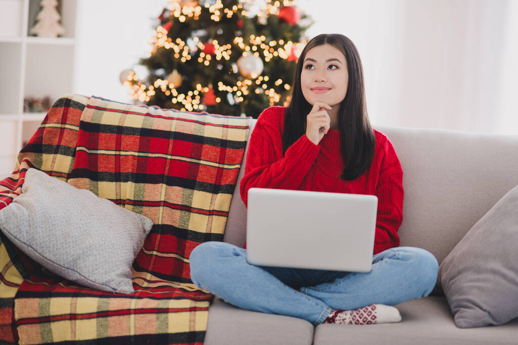 Foto di lucido riflessivo ragazza usura Natale pullover rosso digitando moderno dispositivo braccio mento indoor home room. - Foto, immagini
