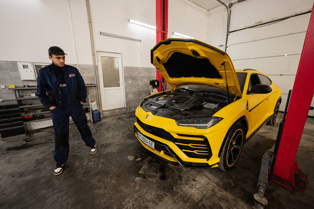 Ternopil, Ukraine - 11. November 2022: Mechaniker steht neben gelbem Lamborghini Urus in Autotankstelle. - Foto, Bild