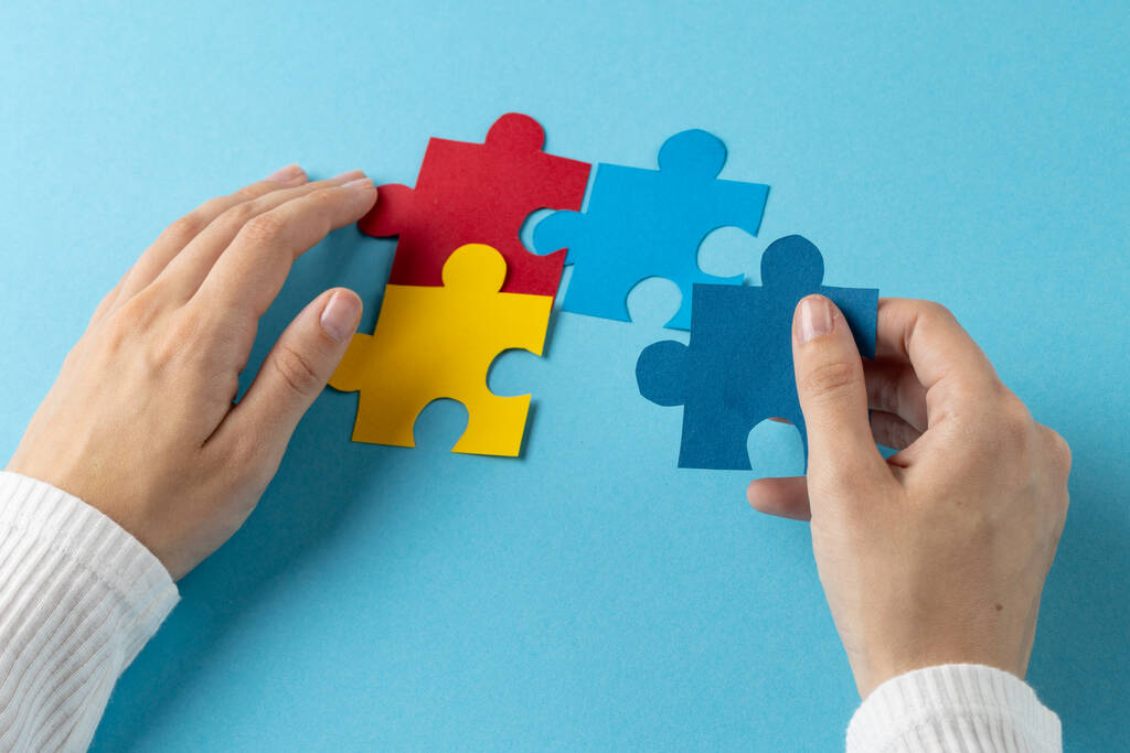 Composition of hands putting jigsaw puzzle pieces together on blue background with copy space. Medical services, healthcare and mental health awareness concept. - Photo, Image