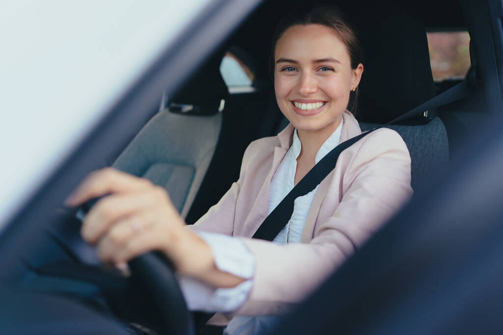 Aufgeregte junge Frau sitzt in ihrem Auto, bereit für eine Fahrt. - Foto, Bild