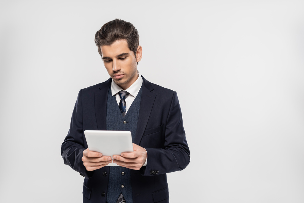 úspěšný podnikatel v obleku pomocí digitálního tabletu izolovaného na šedé  - Fotografie, Obrázek