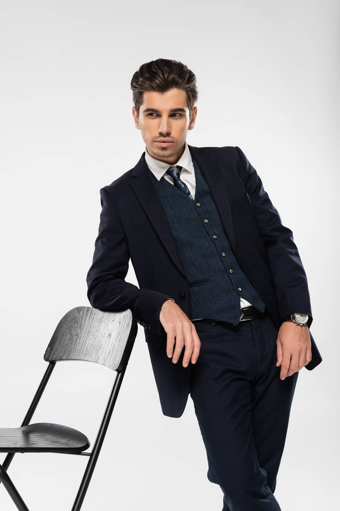 nuori liikemies muodollinen kulumista seisoo lähellä tuoli katsellen pois eristetty harmaa - Valokuva, kuva