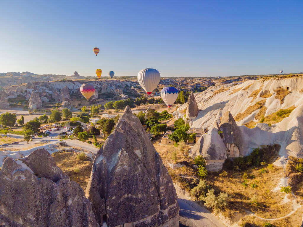 カラフルな熱気球は、ネブシェヒル、ゴーレム、カッパドキアトルコの妖精の煙突の谷で飛んでいます。地下都市と気球観光の壮大なパノラマドローンビュー。高品質. - 写真・画像