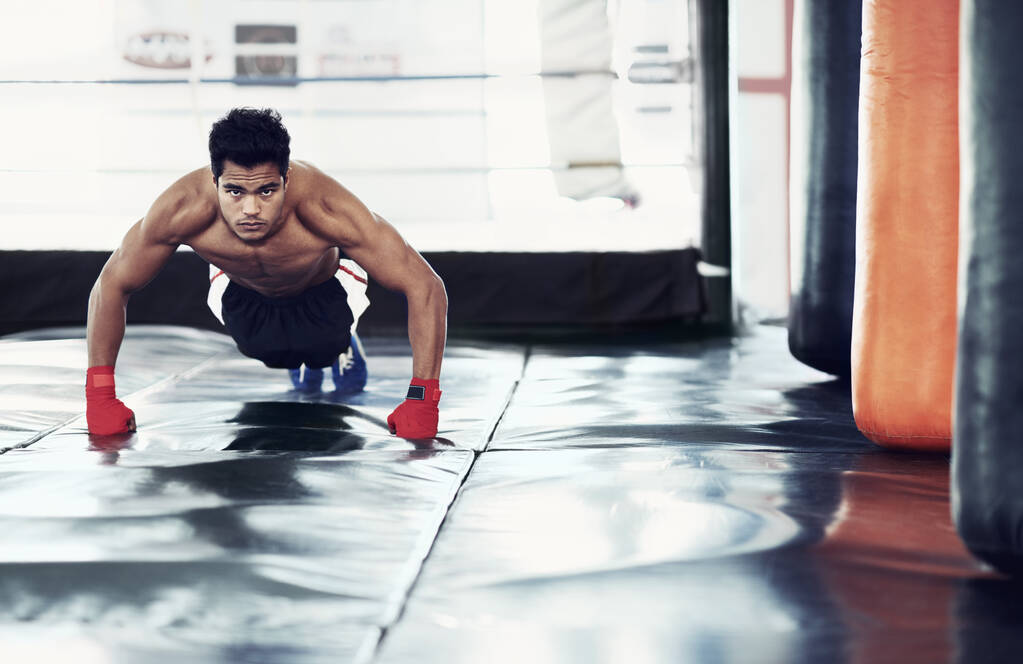 El boxeo es una forma de vida. Un joven boxeador enfocado haciendo flexiones en el gimnasio - Foto, Imagen