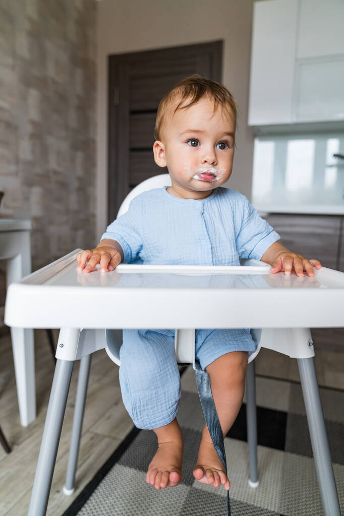 Μωρό τρώει στην κουζίνα άδειο τραπέζι χώρο. Διατροφή του παιδιού. - Φωτογραφία, εικόνα