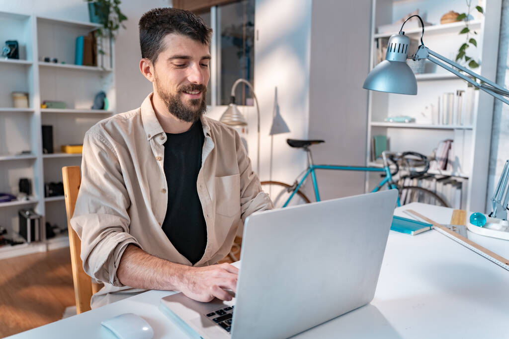 Onnellinen nuori valkoihoinen freelancer työskentelee kannettavan tietokoneen kotona - Yrittäjä mies työskentelee etänä. Laadukas kuva - Valokuva, kuva