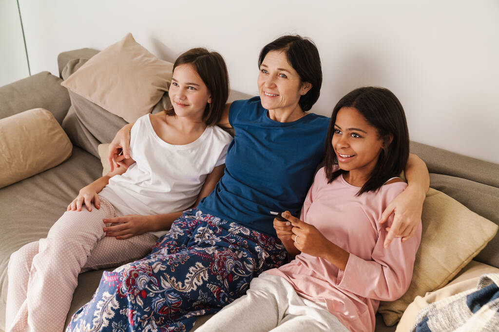 Valkoinen nainen ja hänen tyttärensä katsomassa televisiota, kun lepää sohvalla kotona - Valokuva, kuva