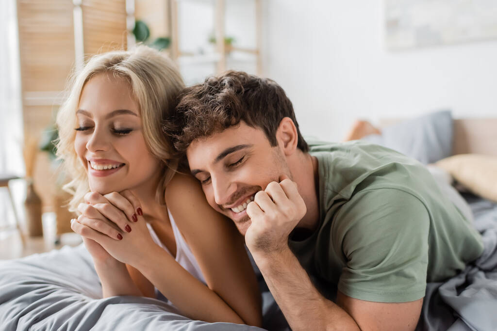 Young couple in pajama lying with closed eyes on bed in morning  - Photo, Image