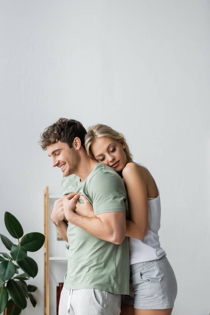 Красивая женщина в пижаме обнимает парня дома утром  - Фото, изображение