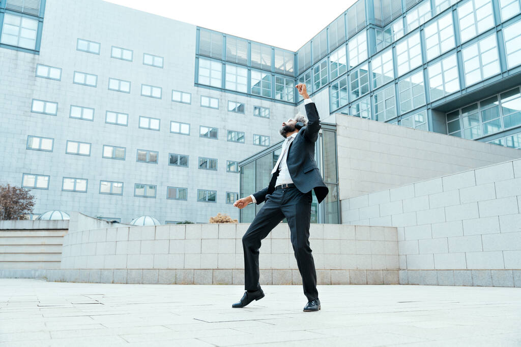 Νεαρός επιχειρηματίας επιχειρηματίας που ακούει μουσική και χορεύει έξω από το γραφείο. Έννοια για την ελευθερία και την επιτυχία στις επιχειρήσεις - Φωτογραφία, εικόνα
