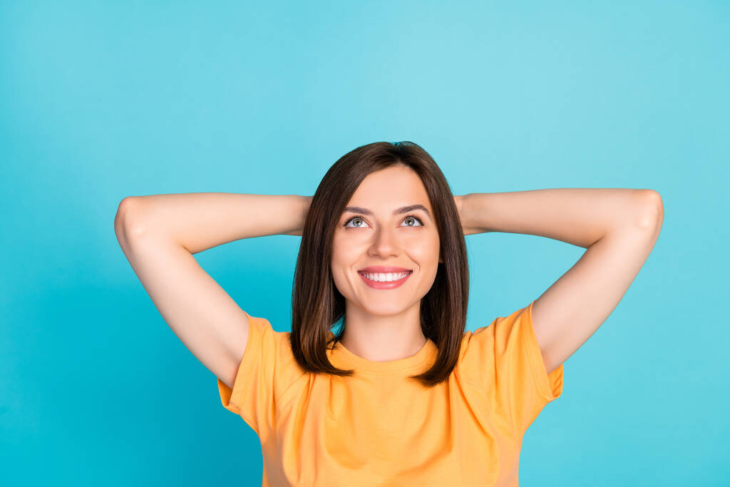 Retrato de mulher satisfeita otimista penteado longo t-shirt amarela olhar mãos espaço vazio atrás da cabeça isolada no fundo de cor azul. - Foto, Imagem