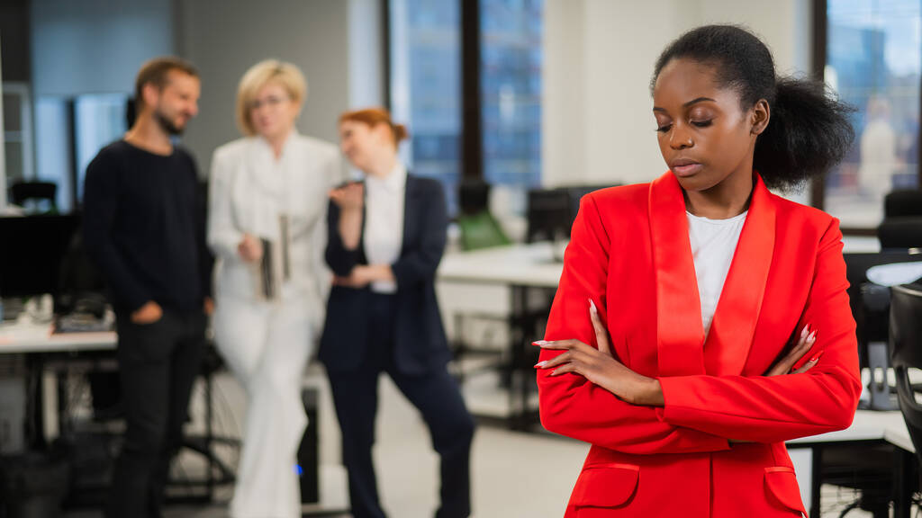La joven africana está molesta por el ridículo de sus colegas. Discriminación racial en la oficina - Foto, imagen